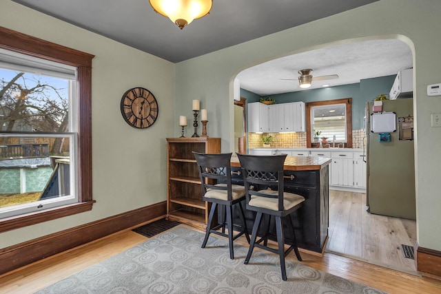 kitchen with arched walkways, white cabinets, tasteful backsplash, and a wealth of natural light