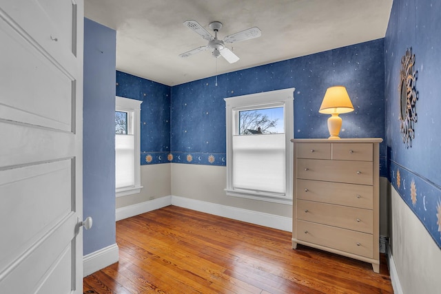 bedroom with ceiling fan, wallpapered walls, baseboards, and hardwood / wood-style flooring