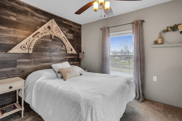 bedroom with ceiling fan, wood walls, and carpet flooring