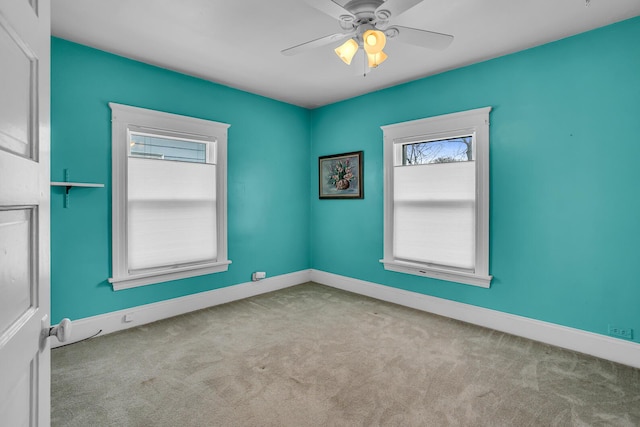 carpeted empty room featuring baseboards and ceiling fan