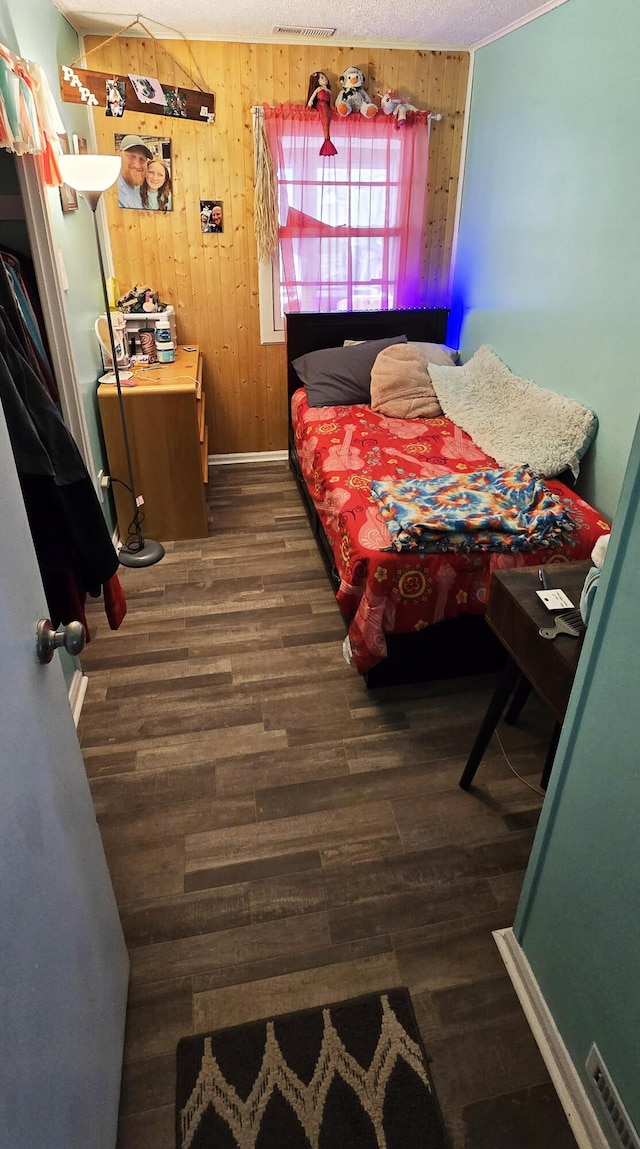 bedroom with baseboards, wood finished floors, and wood walls