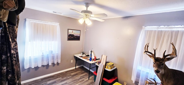 home office with visible vents, crown molding, baseboards, wood finished floors, and a ceiling fan