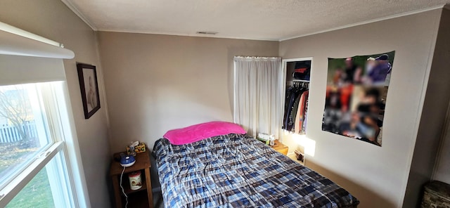 bedroom featuring crown molding, visible vents, and a textured ceiling