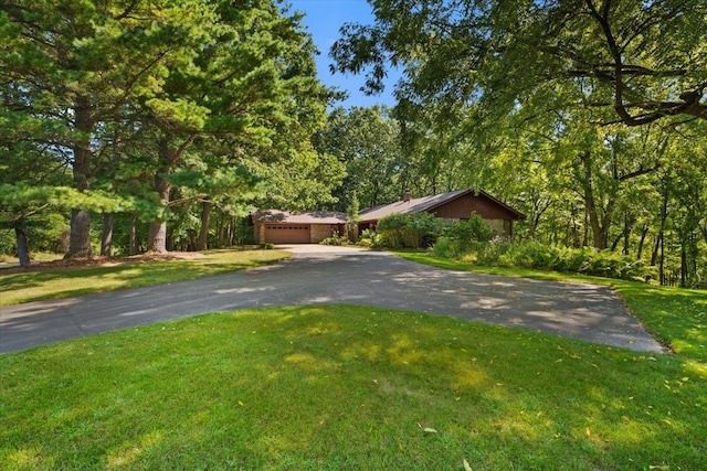 view of front of house with aphalt driveway, an attached garage, and a front lawn