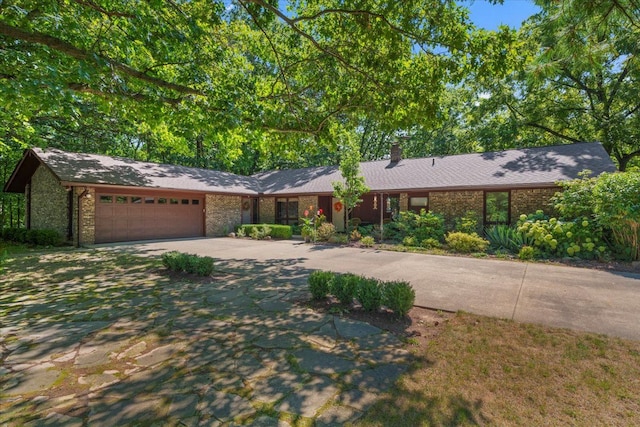 view of front of home with a garage, a chimney, and driveway