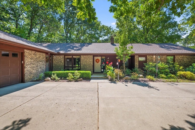 ranch-style home featuring a garage, brick siding, a chimney, and driveway