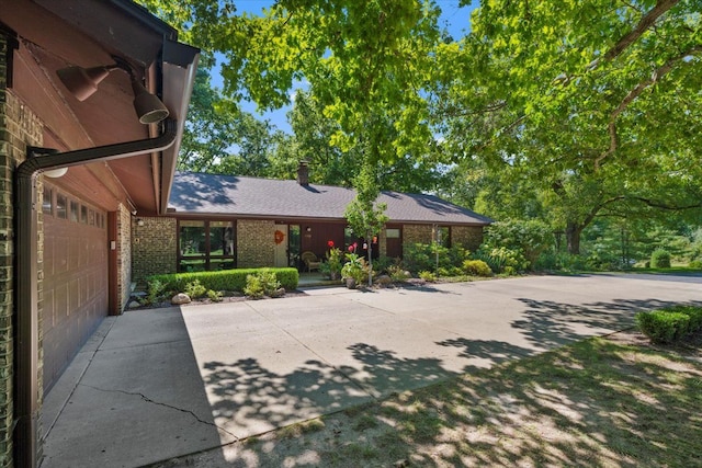 view of front facade featuring brick siding, an attached garage, and driveway