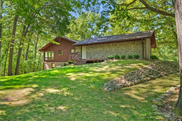 rear view of property featuring brick siding, a lawn, and a wooden deck