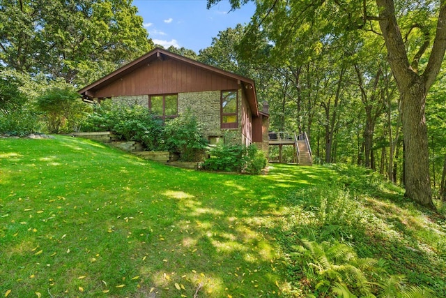 view of home's exterior with stairway, a lawn, a deck, and brick siding