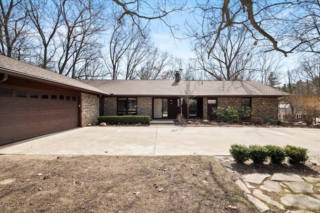 view of front facade with a garage, brick siding, a chimney, and driveway