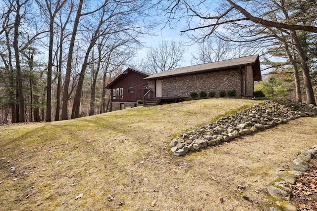 view of property exterior featuring brick siding, a lawn, and a deck