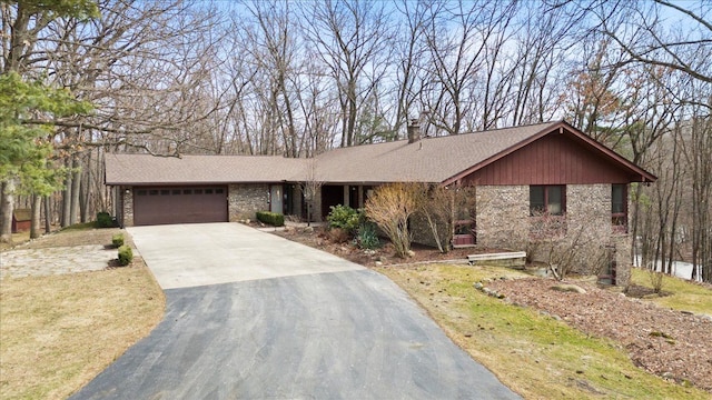 view of front facade with driveway, a shingled roof, a chimney, a garage, and brick siding