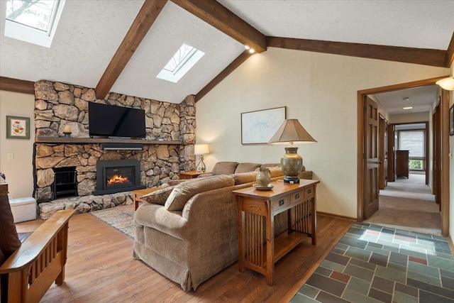 living area featuring hardwood / wood-style flooring, vaulted ceiling with skylight, a fireplace, and a textured ceiling