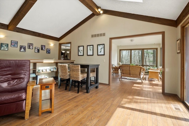 dining space with hardwood / wood-style flooring, baseboards, visible vents, and beam ceiling