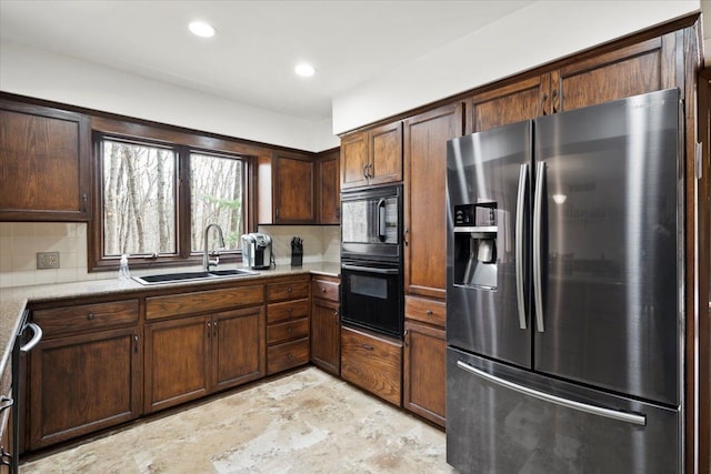 kitchen featuring backsplash, light countertops, recessed lighting, black appliances, and a sink