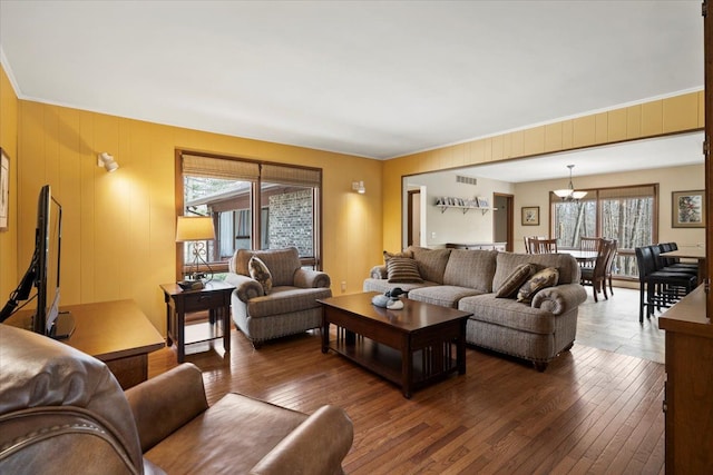 living area featuring visible vents, an inviting chandelier, hardwood / wood-style floors, and ornamental molding