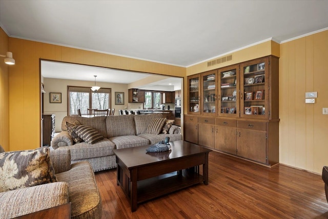 living area featuring visible vents, dark wood finished floors, and crown molding