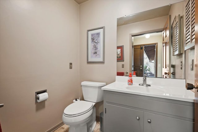 bathroom with toilet, vanity, and baseboards