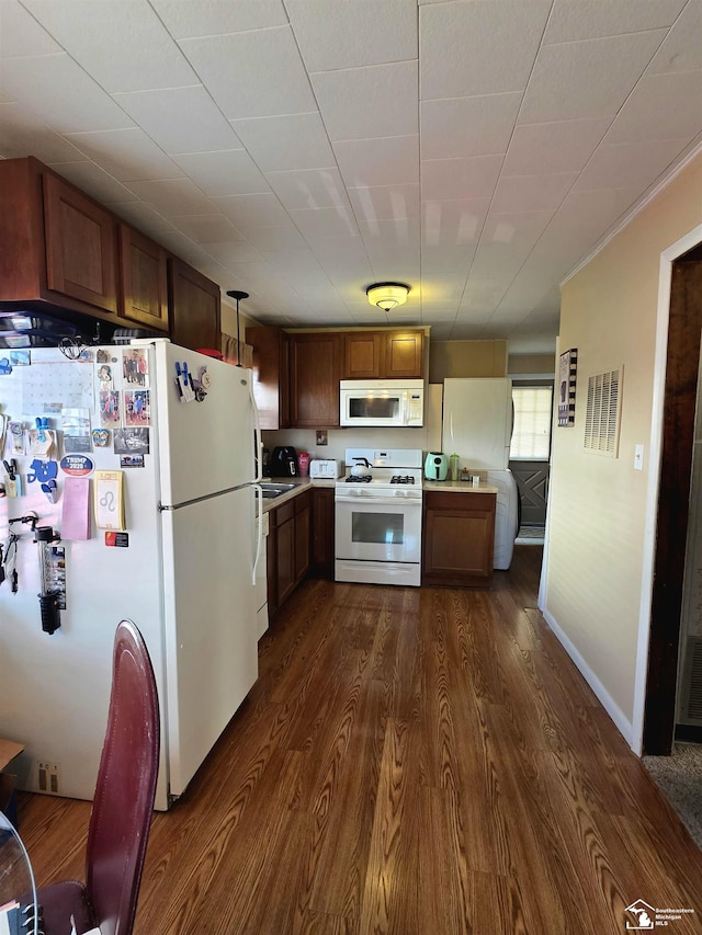 kitchen with visible vents, baseboards, light countertops, dark wood-style floors, and white appliances