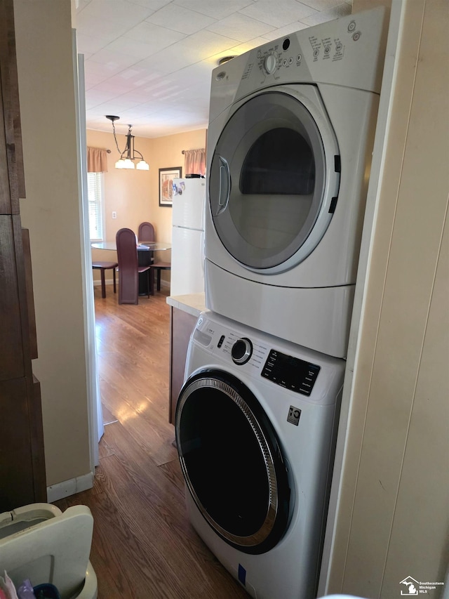 washroom featuring laundry area, stacked washer and dryer, and wood finished floors