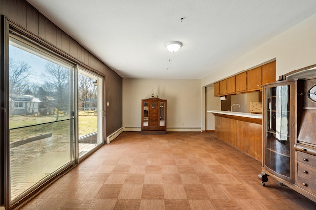 kitchen featuring baseboards, brown cabinets, baseboard heating, and light countertops