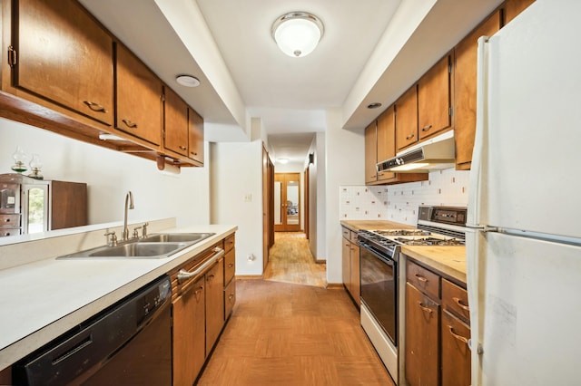 kitchen featuring gas stove, freestanding refrigerator, a sink, under cabinet range hood, and dishwasher