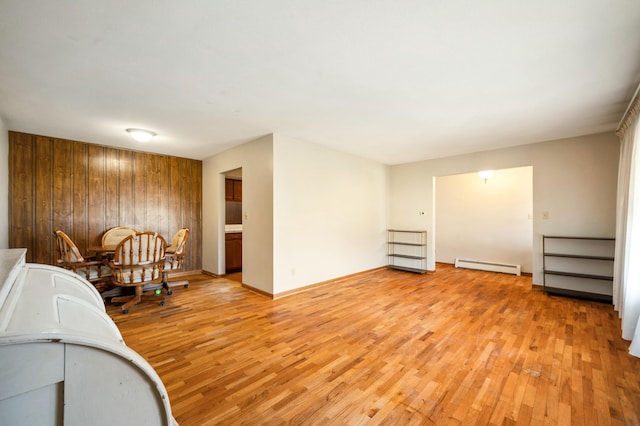 interior space with a baseboard heating unit, baseboards, and light wood finished floors