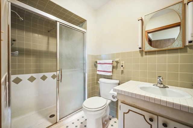 full bath featuring vanity, a wainscoted wall, a stall shower, tile walls, and toilet