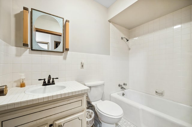 bathroom with tile walls, toilet, wainscoting, bathtub / shower combination, and vanity