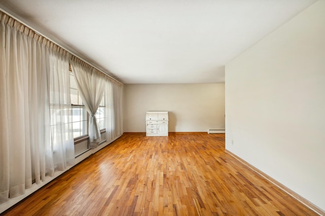 empty room with a baseboard radiator and wood finished floors