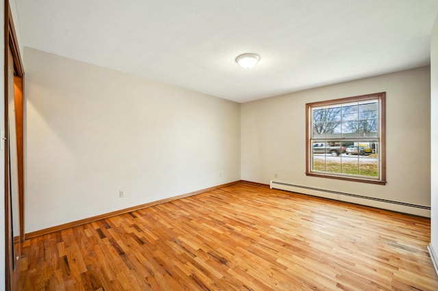 empty room featuring light wood-style flooring, baseboards, and a baseboard radiator