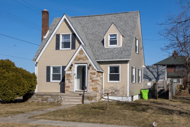 view of front facade featuring roof with shingles and a front yard