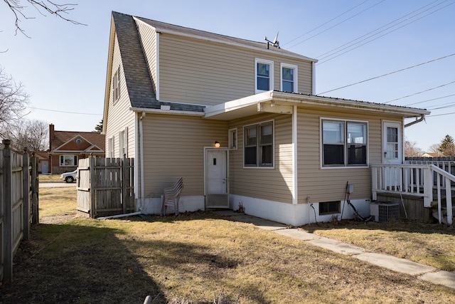 back of property with central AC unit, fence, a lawn, and roof with shingles