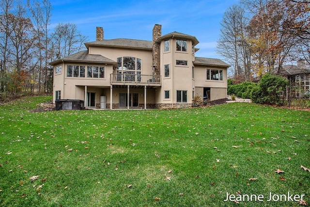 rear view of property with a lawn, a chimney, and stucco siding