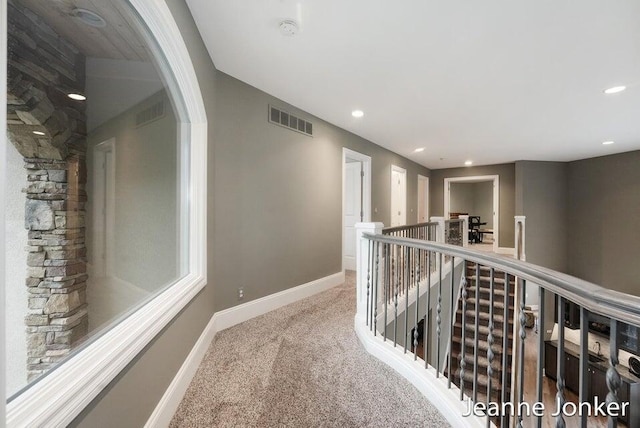 corridor featuring visible vents, baseboards, an upstairs landing, carpet flooring, and recessed lighting