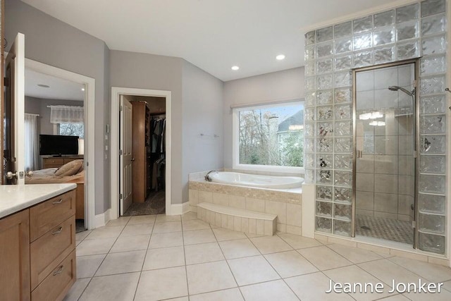 full bathroom with tile patterned floors, a walk in closet, a garden tub, a tile shower, and vanity