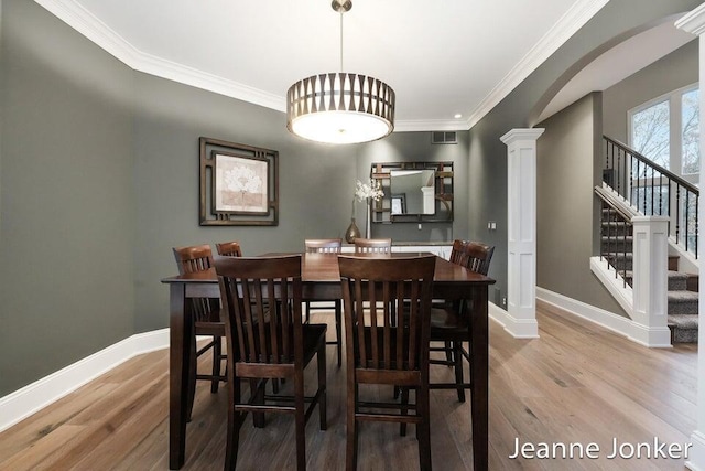 dining area with baseboards, arched walkways, and wood finished floors