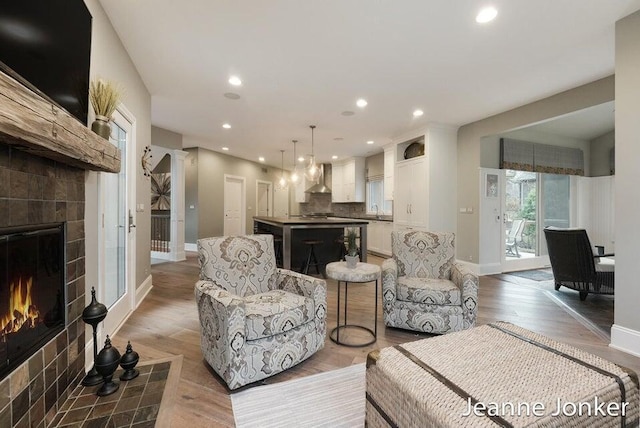 living room featuring recessed lighting, a tile fireplace, and light wood-type flooring