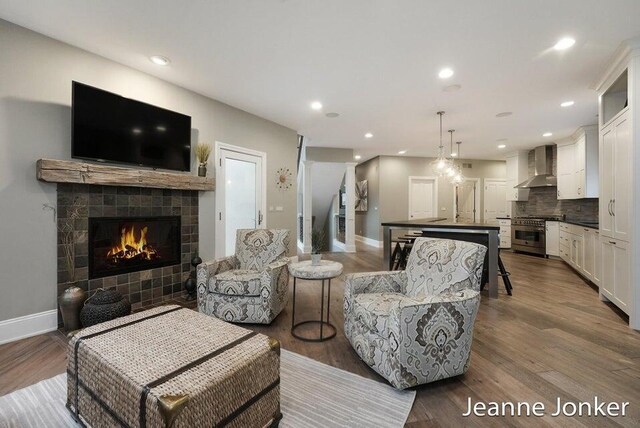 living area with recessed lighting, a fireplace, baseboards, and wood finished floors