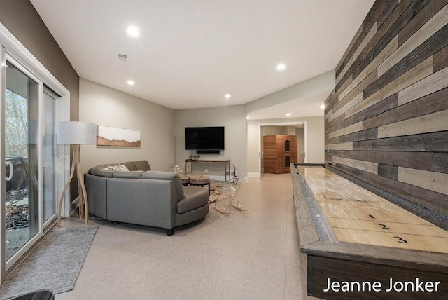 living area featuring wooden walls, visible vents, recessed lighting, and light floors