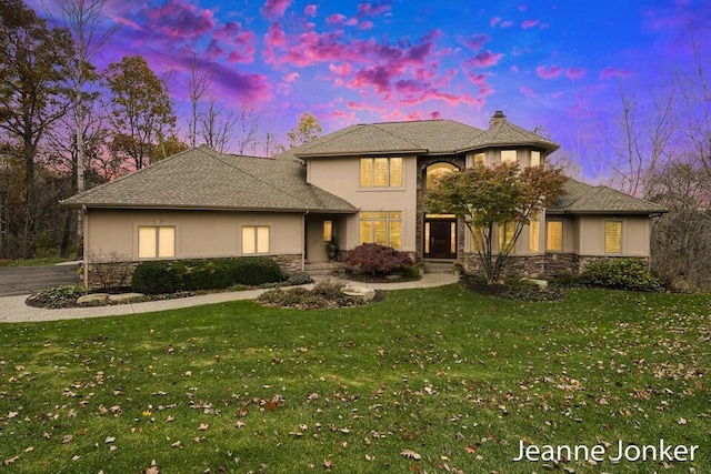 view of front of property with stone siding, stucco siding, and a lawn