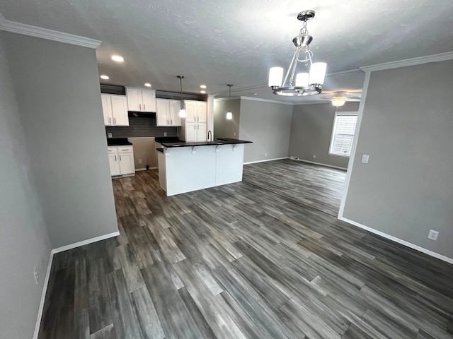 kitchen with dark wood-style flooring, white cabinetry, dark countertops, open floor plan, and backsplash