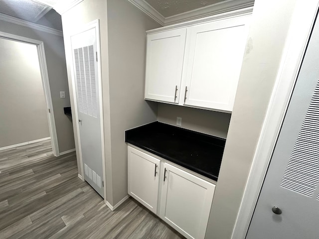 bar with a heating unit, baseboards, ornamental molding, and light wood finished floors