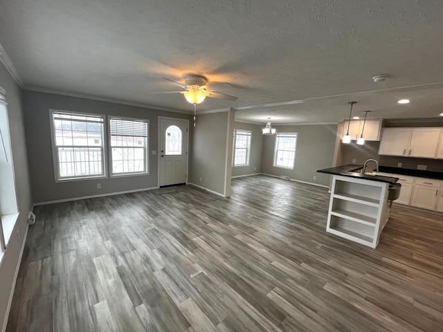 interior space with dark countertops, open floor plan, ornamental molding, white cabinetry, and dark wood-style flooring