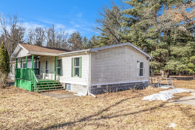 view of side of property with covered porch and a shingled roof