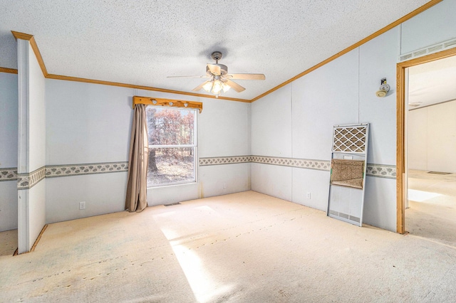 carpeted spare room featuring visible vents, a textured ceiling, crown molding, and a ceiling fan