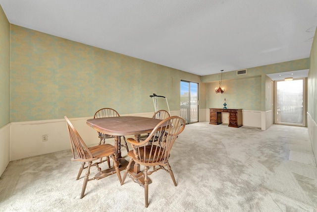 dining room with wallpapered walls, light colored carpet, and visible vents