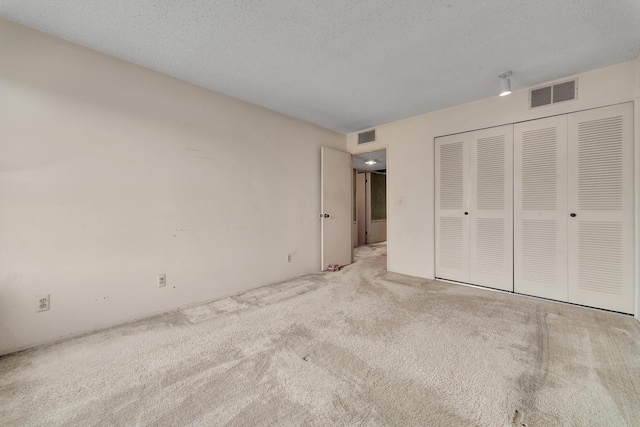 unfurnished bedroom featuring a closet, visible vents, carpet floors, and a textured ceiling