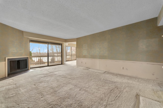 unfurnished living room featuring a textured ceiling and carpet flooring