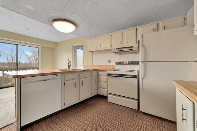 kitchen featuring a sink, under cabinet range hood, white appliances, a peninsula, and light countertops